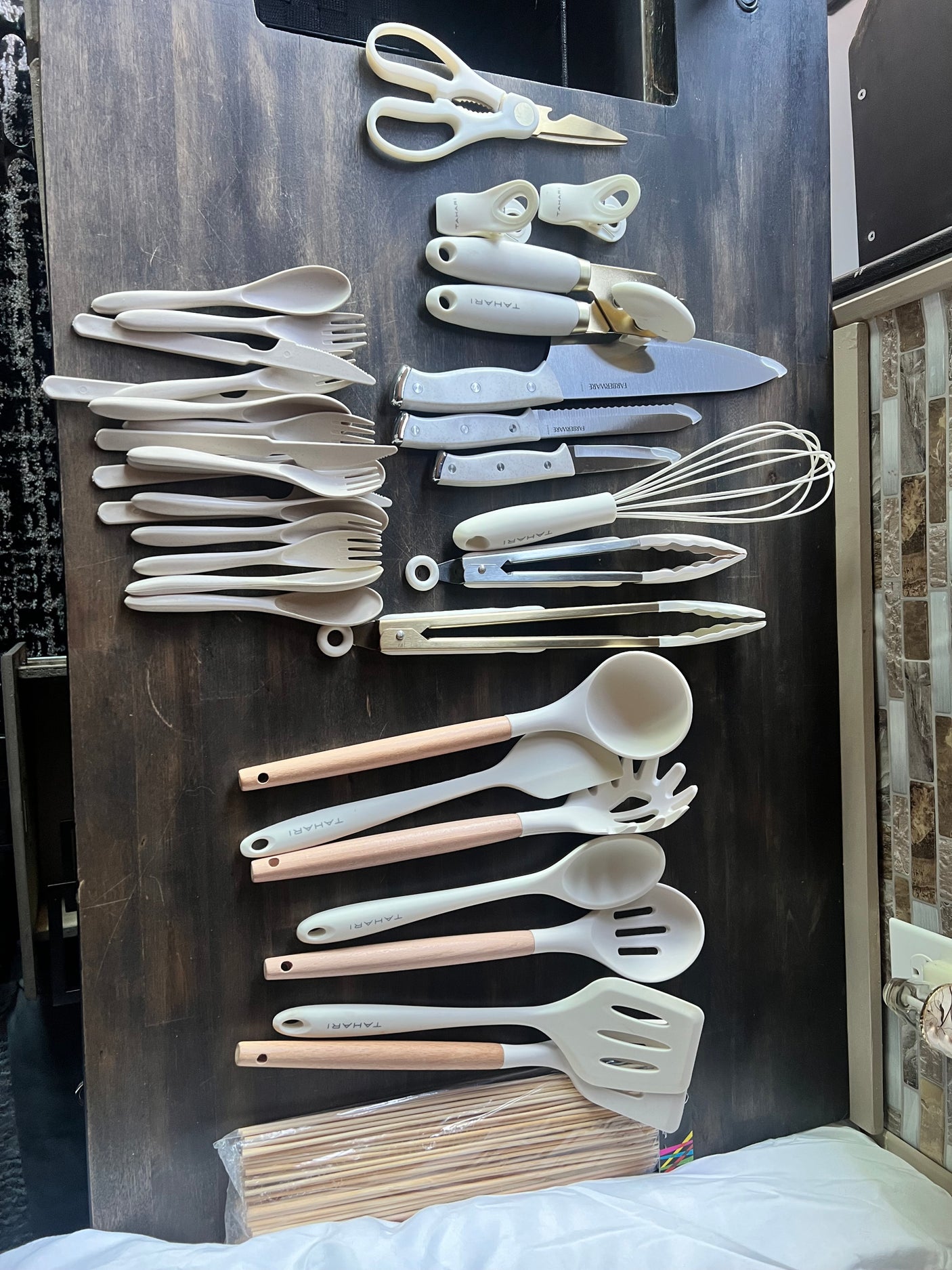 Fully stocked RV rental kitchen with new white cooking utensils, knives, and cutlery for your road trip meals.