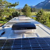 RV rental with solar panels and roof vents for off-grid adventure, set against a stunning mountain lake backdrop.