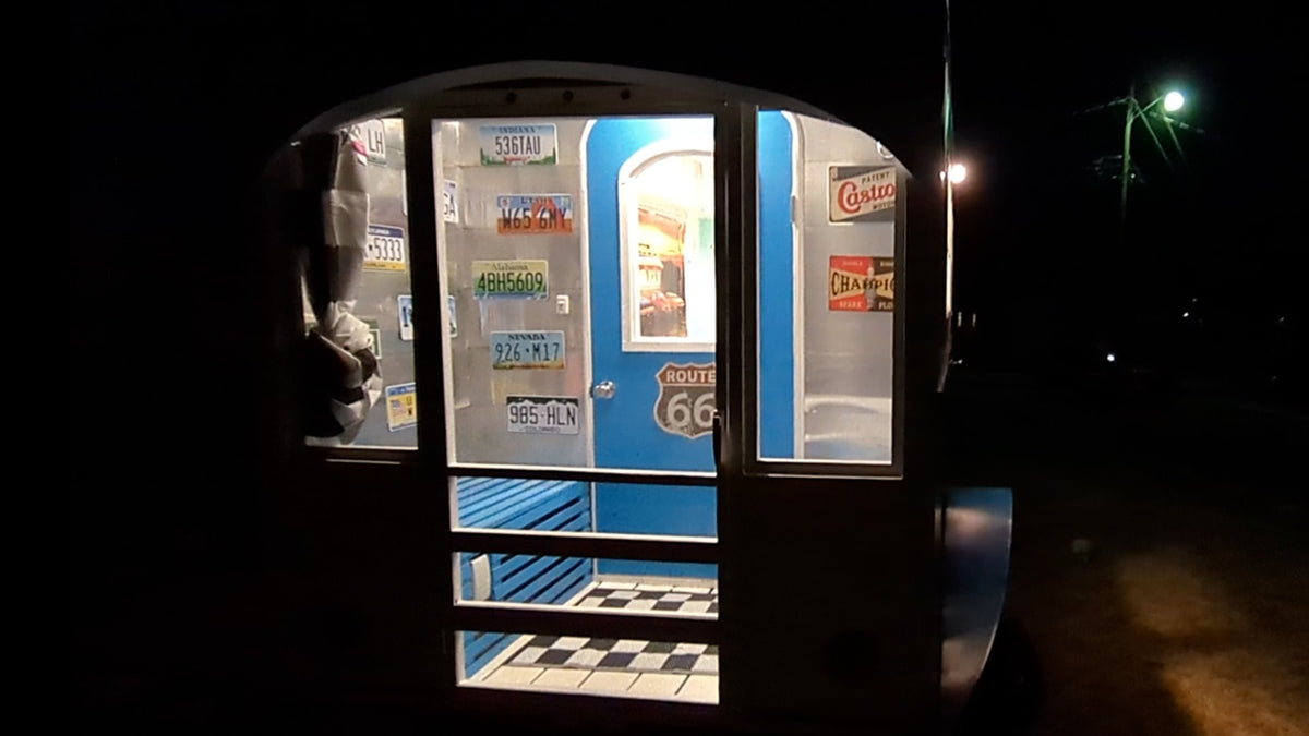 Experience a retro road trip! This unique **rv rental** trailer glows at night, showcasing Route 66 decor & vintage license plates. — photo 3