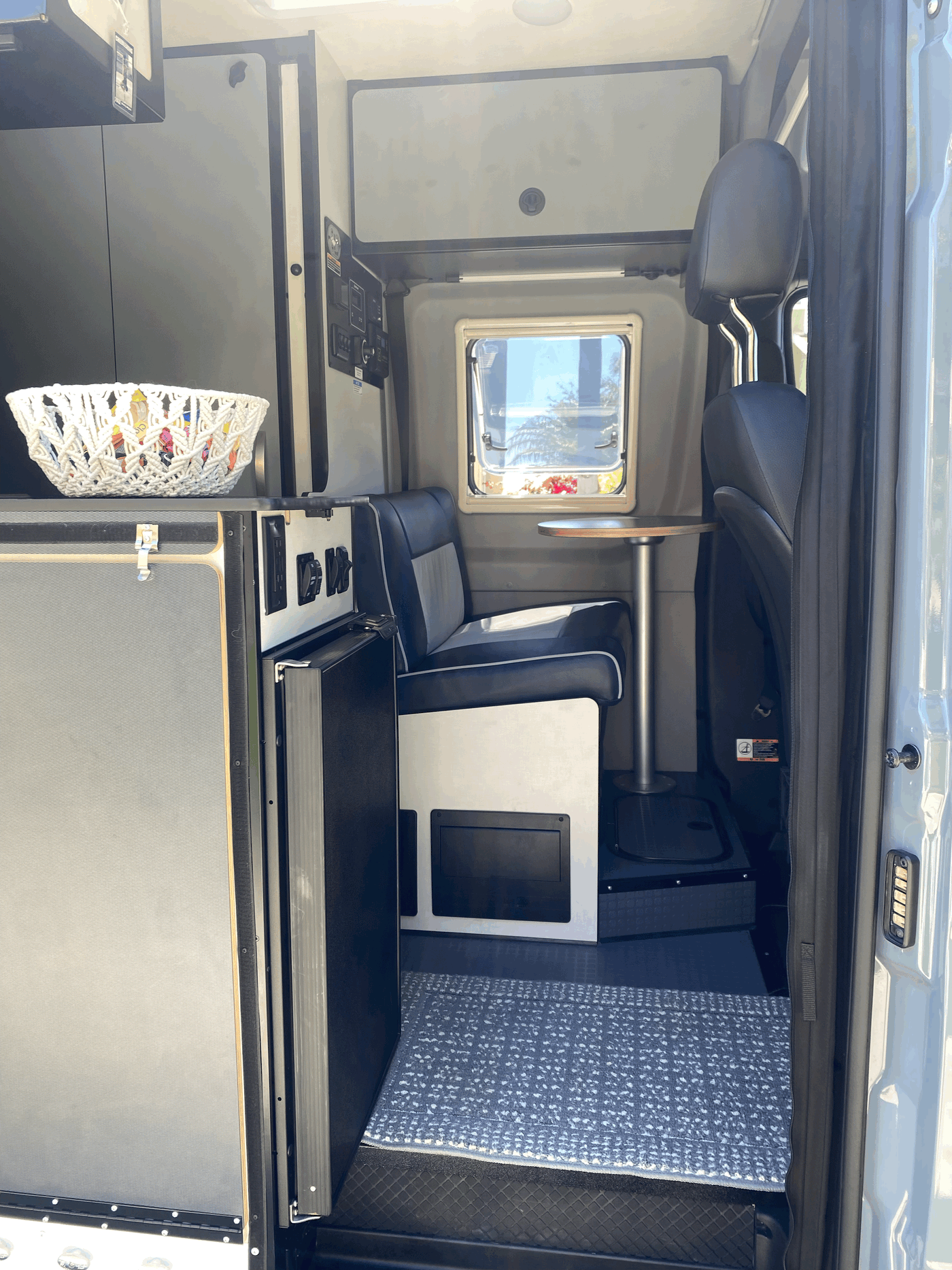RV rental interior: Compact camper van with a cozy dining nook, kitchenette, and smart controls. — photo 10