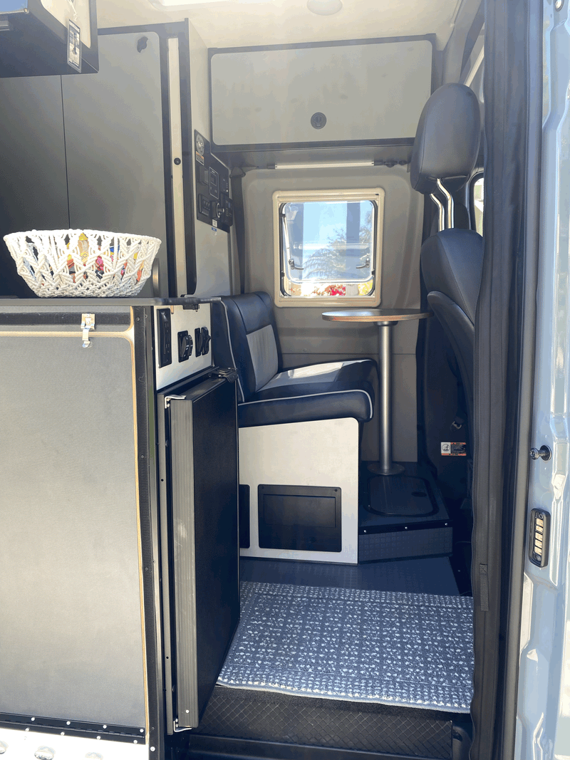 RV rental interior: Compact camper van with a cozy dining nook, kitchenette, and smart controls. — photo 10