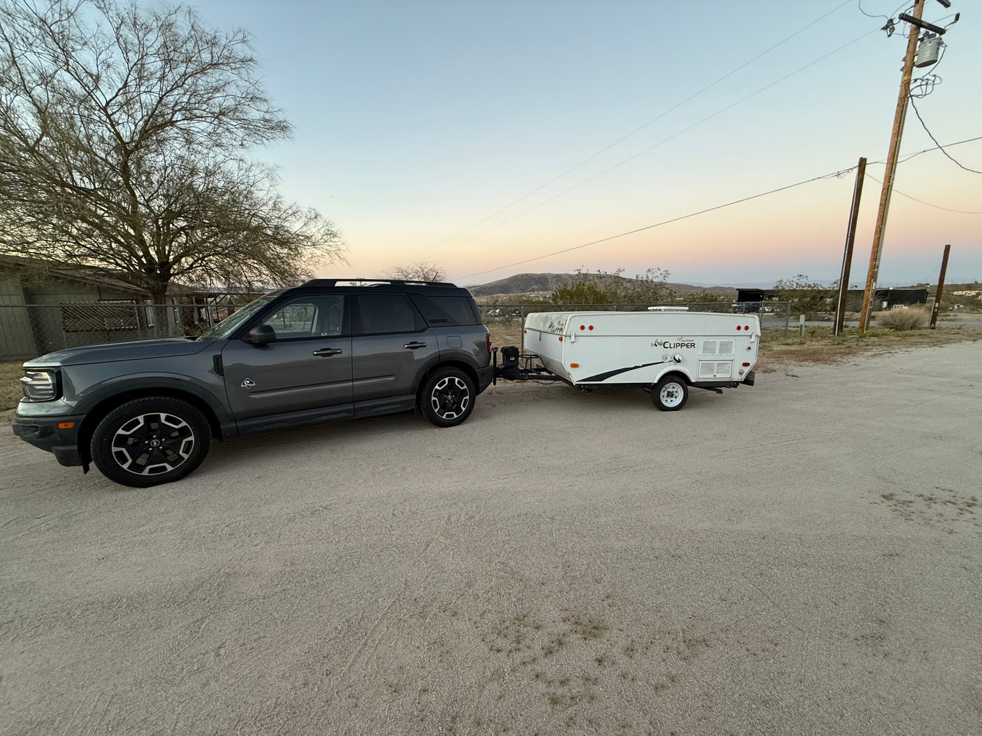 Gray Ford Bronco Sport SUV towing a white Coachmen Clipper pop-up camper, suitable for an rv rental adventure.