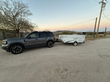 Gray Ford Bronco Sport SUV towing a white Coachmen Clipper pop-up camper, suitable for an rv rental adventure.