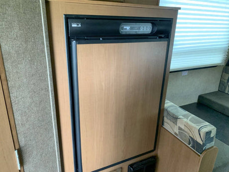 Compact, wood-paneled refrigerator and dinette inside an RV rental. Perfect for cozy travel adventures!