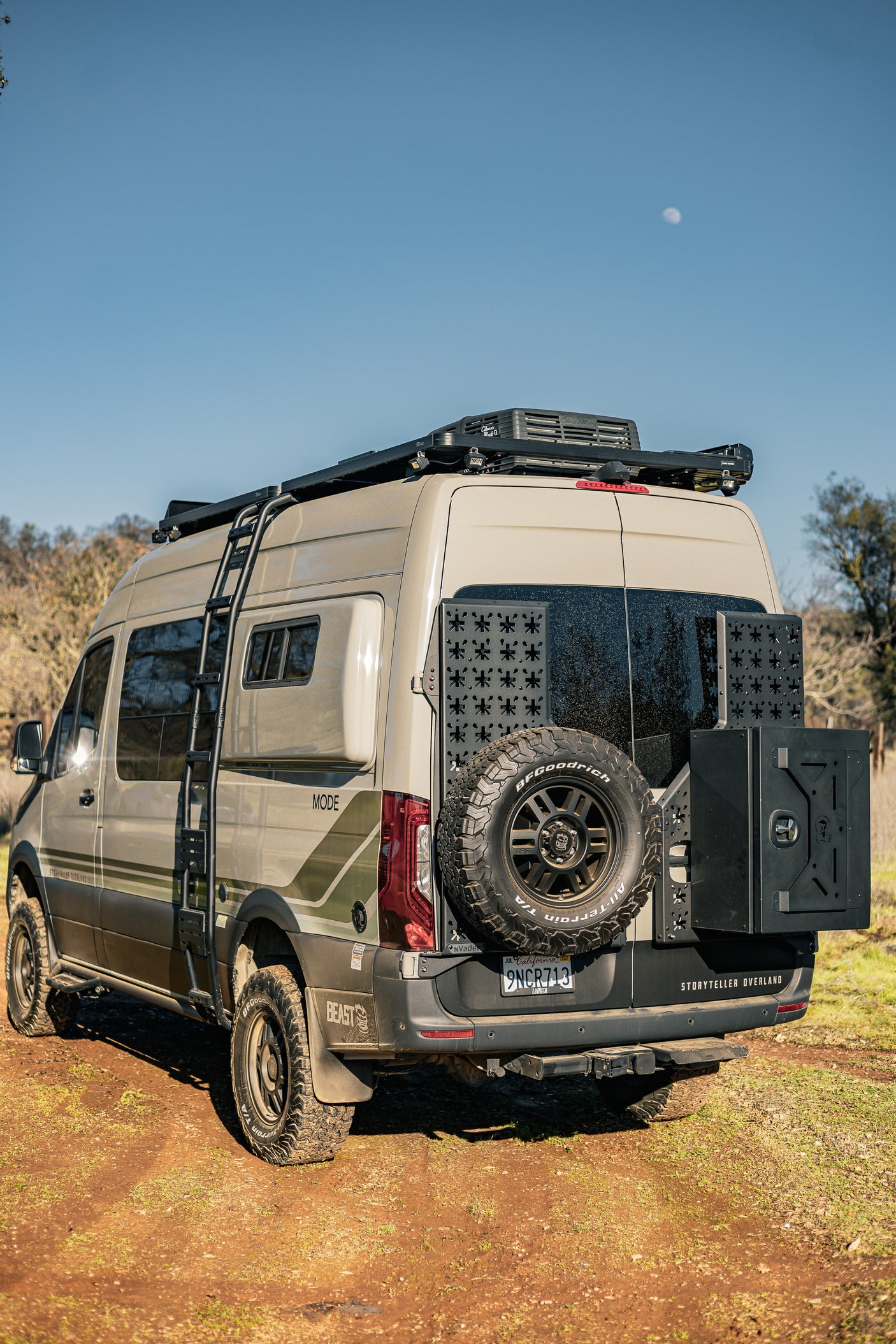 Tan Storyteller Overland adventure van, an ideal rv rental, equipped for off-grid travel, on a dirt path.