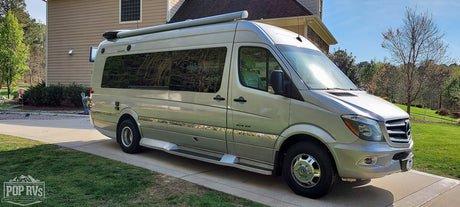 Full side view of a silver Mercedes-Benz Sprinter Class B RV, parked on a driveway, ready for an rv rental.