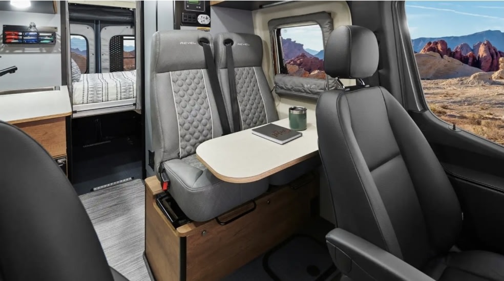 Experience an RV rental! Interior of a campervan with dining area, bed, and desert views, perfect for travel adventures. — photo 10