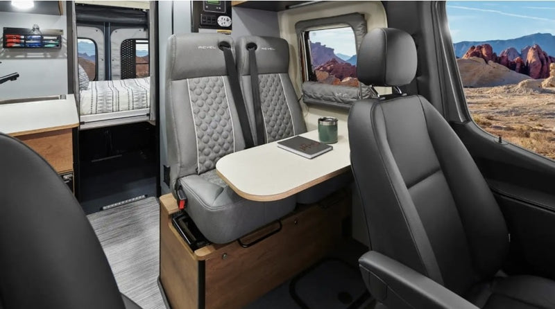 Experience an RV rental! Interior of a campervan with dining area, bed, and desert views, perfect for travel adventures. — photo 10