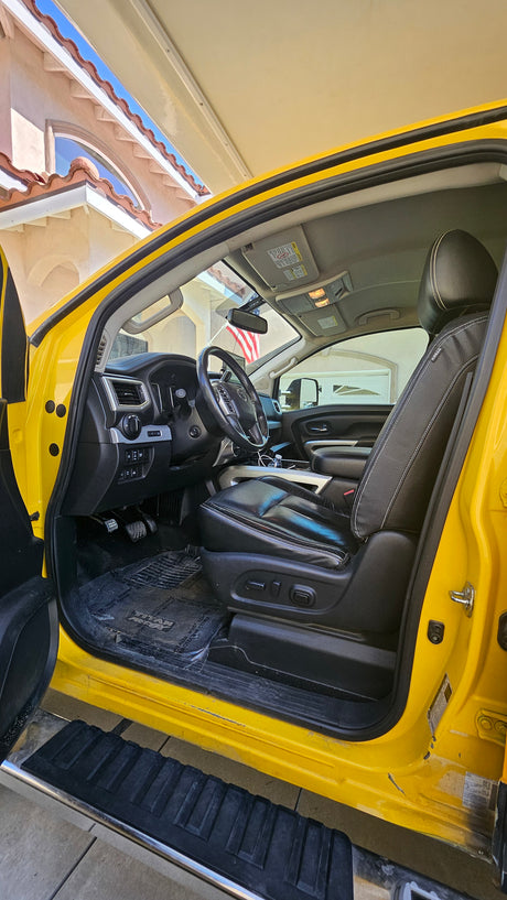 Inside a vibrant yellow truck, driver's door open revealing the dashboard, seat, and floor mats. Perfect for an RV rental journey.