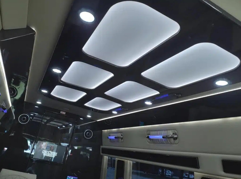 Modern luxury RV rental interior with sleek ceiling panels, ambient lighting, and entertainment screen for premium travel.