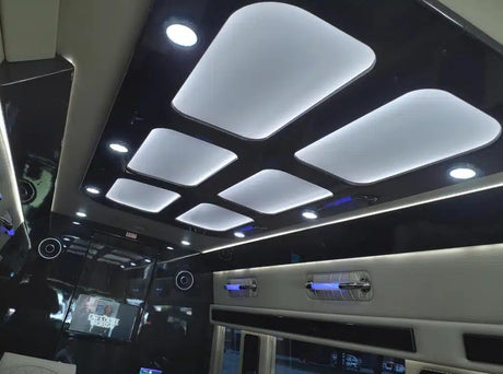 Modern luxury RV rental interior with sleek ceiling panels, ambient lighting, and entertainment screen for premium travel.