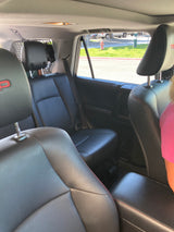 View from a spacious SUV's black leather interior, ideal for your RV rental travels. Cargo barrier visible behind rear seats.