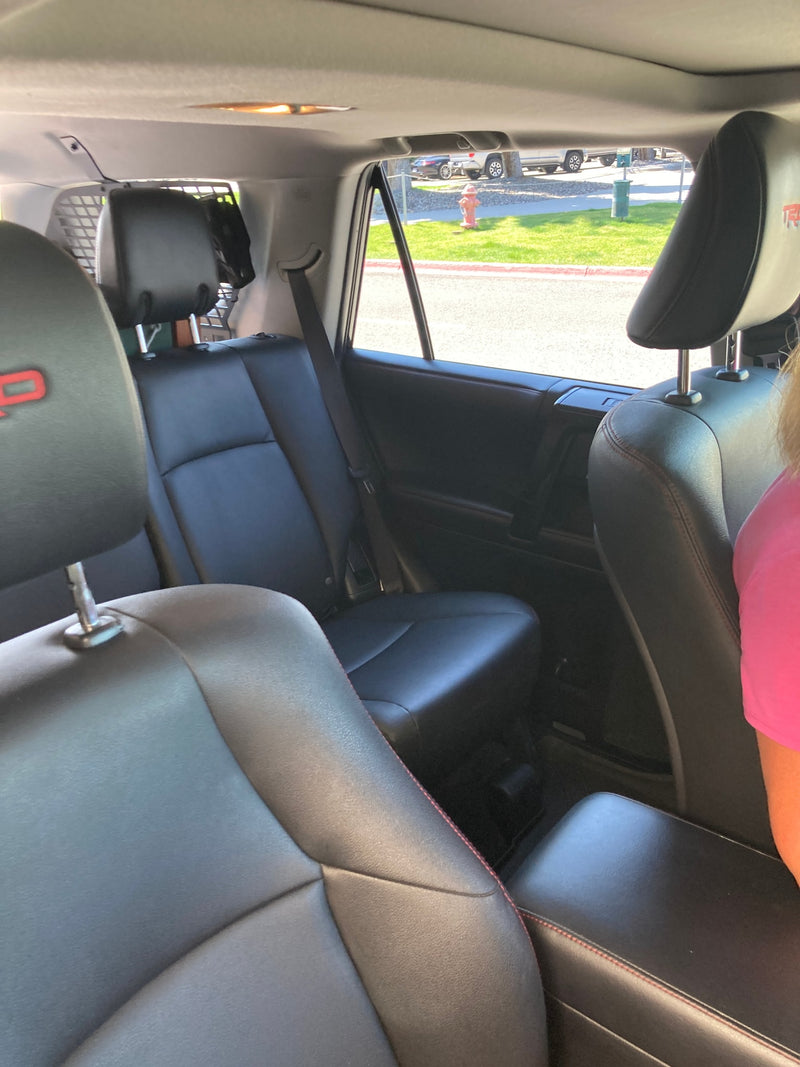 View from a spacious SUV's black leather interior, ideal for your RV rental travels. Cargo barrier visible behind rear seats. — photo 10