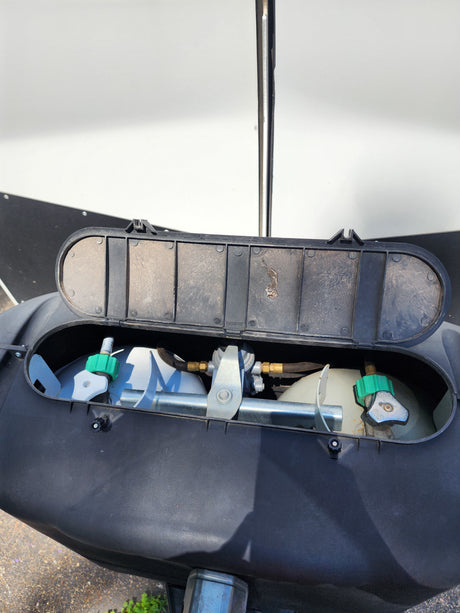 Open RV propane tank cover showing dual tanks & regulator. A key feature for your rv rental trip.