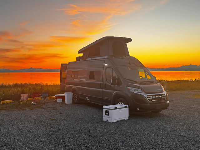 Experience your RV rental adventure! Camper van parked at a scenic waterfront campsite with a stunning sunset and mountains.|This gray Winnebago Solis rv rental