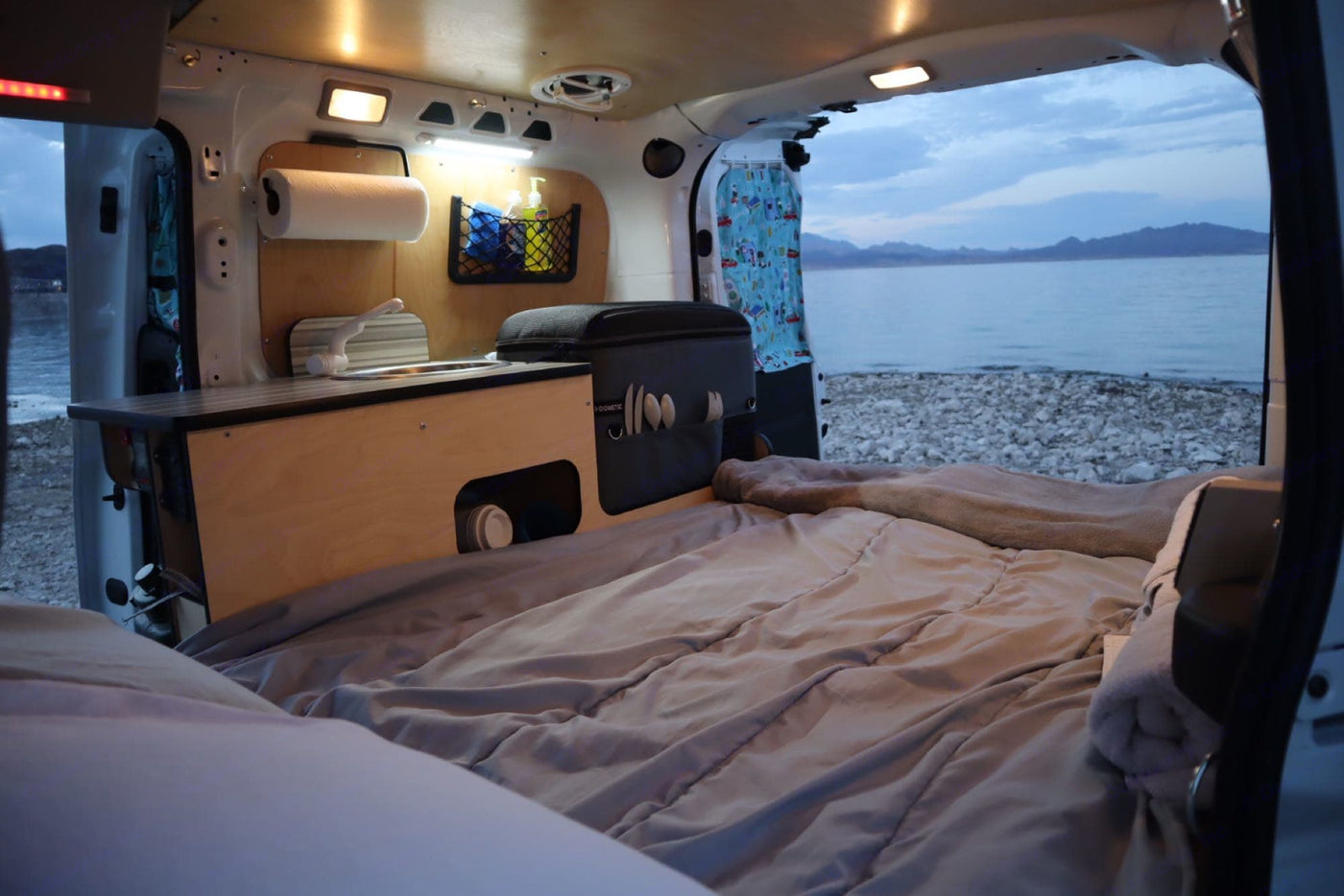  rests at a scenic viewpoint. Red rock mountains rise under an overcast sky.|Lakeside white camper van — photo 2