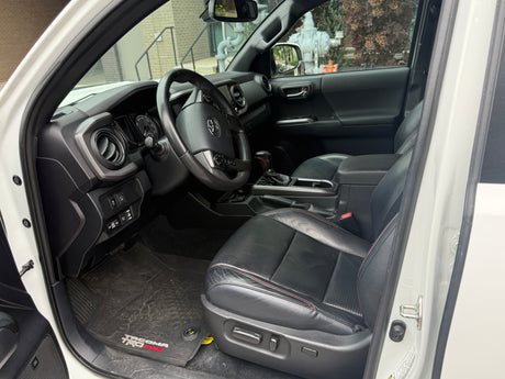Driver's view of a clean, modern truck's black interior with leather seats, dashboard, and steering wheel. A comfortable alternative to an rv rental.