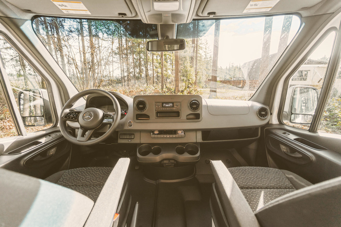 RV rental: View from inside a van's front cabin, showing the dashboard, steering wheel, and road ahead through the windshield.