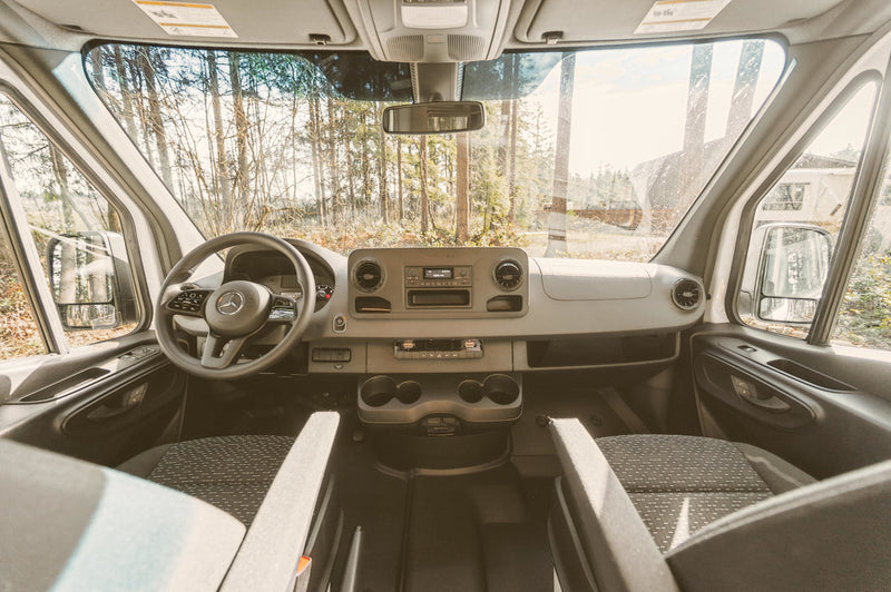 RV rental: View from inside a van's front cabin, showing the dashboard, steering wheel, and road ahead through the windshield. — photo 13