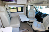 Bright RV rental interior: cream leather seats, a functional table, and the driver's area for comfortable travel.
