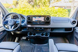 Modern Mercedes-Benz rv rental cockpit with carbon fiber accents. Features detailed steering wheel, large nav screen, and cup holders.