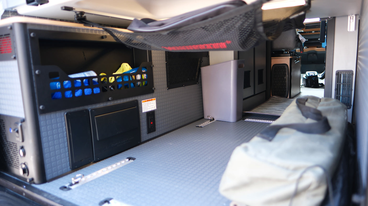 RV rental cargo area with modular storage, power system, textured floor, and tie-down tracks for organized travel.