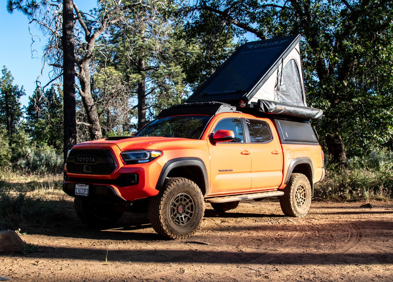  an off-road overlanding beast with rooftop tent & canopy. Perfect for your adventure-ready RV rental.|Red Toyota Tacoma truck with deployed rooftop tent and awning. A versatile overland camp setup — photo 7
