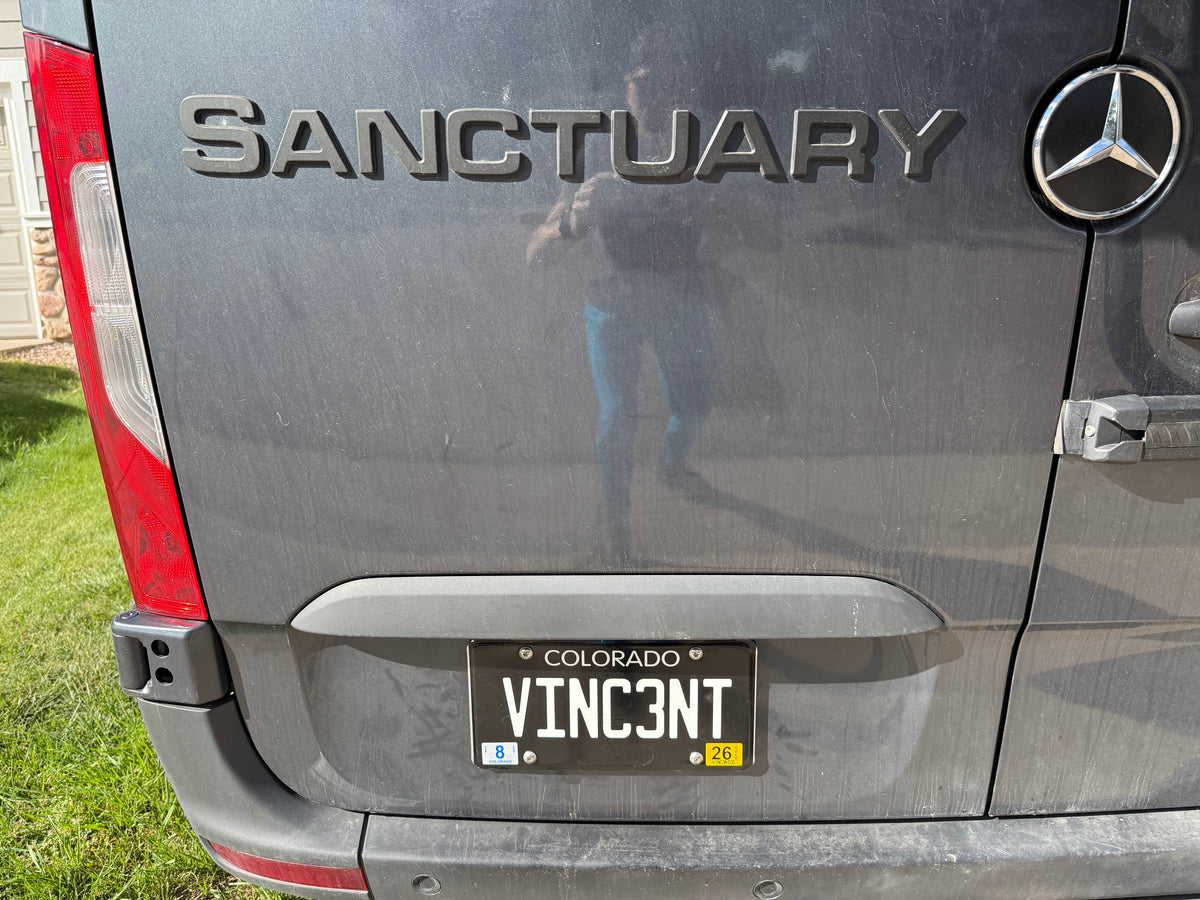 Rear of a dusty gray Mercedes-Benz RV rental van, labeled "SANCTUARY," with a custom Colorado "VINC3NT" license plate. — photo 4