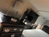 Cozy RV rental interior with a dresser, lamp, mounted TV, and comfortable bed. Perfect for van life.