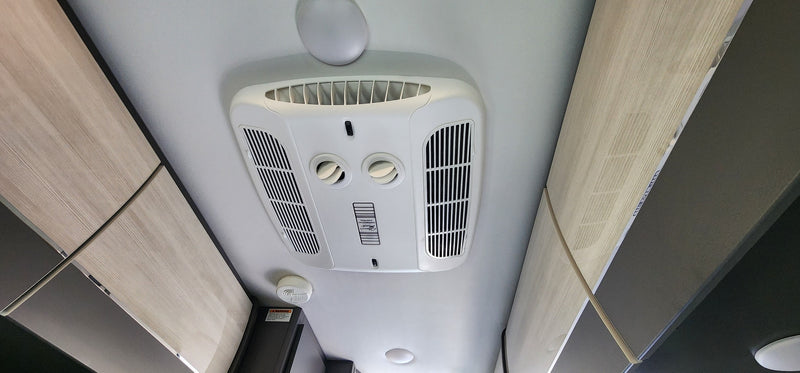 An RV rental's ceiling featuring a white Dometic air conditioner, adjustable vents, overhead cabinets, and a smoke detector. — photo 7