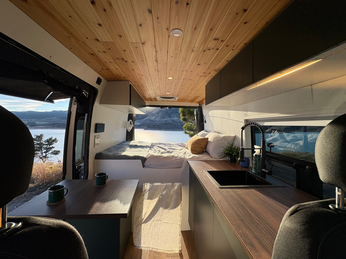 Experience comfortable mobile living in this cozy rv rental interior, featuring a wooden ceiling, bed, kitchenette, and scenic lake view. — photo 7