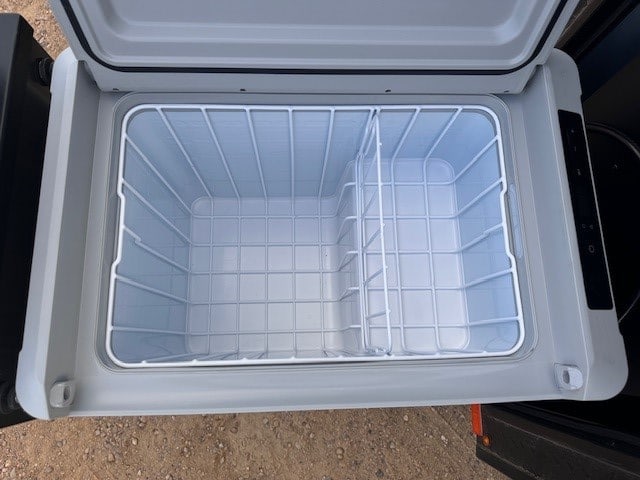 Inside an empty RV rental portable fridge/cooler, ideal for camping trips. Features wire baskets & dual compartments.