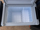 Inside an empty RV rental portable fridge/cooler, ideal for camping trips. Features wire baskets & dual compartments.