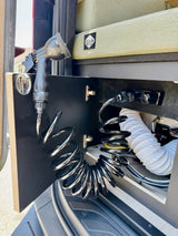 RV rental: A camper van's compact outdoor shower with coiled hose and nozzle, neatly stored inside a side cabinet.