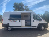 White camper van, side door open to reveal a custom-built interior. A versatile RV rental for road trips.