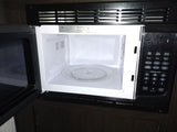 A built-in microwave oven, commonly found in an RV rental, with its door open revealing the interior and control panel.