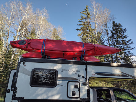 Two red kayaks strapped atop an **rv rental** truck camper, ready for wilderness travel and water sports adventures.