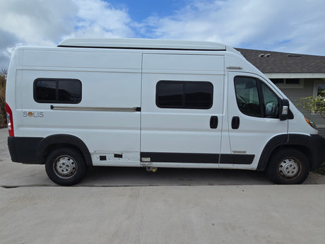 A white Winnebago Solis camper van, perfect for RV rental, parked on concrete outdoors under a blue sky.