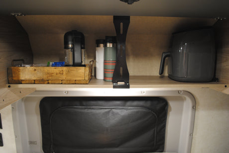 RV rental interior: A compact shelf holds a coffee maker, an air fryer, and travel mugs, neatly organized for mobile living.