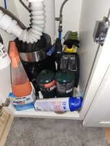 Inside an **RV rental**: Propane tanks, holding tank treatment, toaster, and cleaning items stored under the sink.