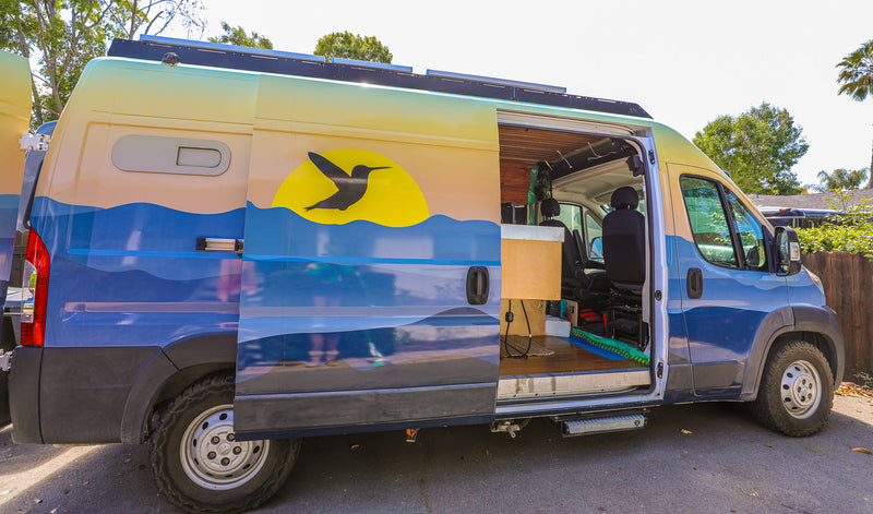 Vibrant rv rental camper van, custom-painted with a sunset and hummingbird, side door open to reveal its adventure-ready interior. — photo 14