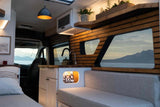 Cozy RV rental interior with a functional kitchen, living area, and stunning lake and mountain views through the windows.