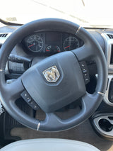 Interior of an RV rental showing the steering wheel with Ram logo, dashboard, and controls.