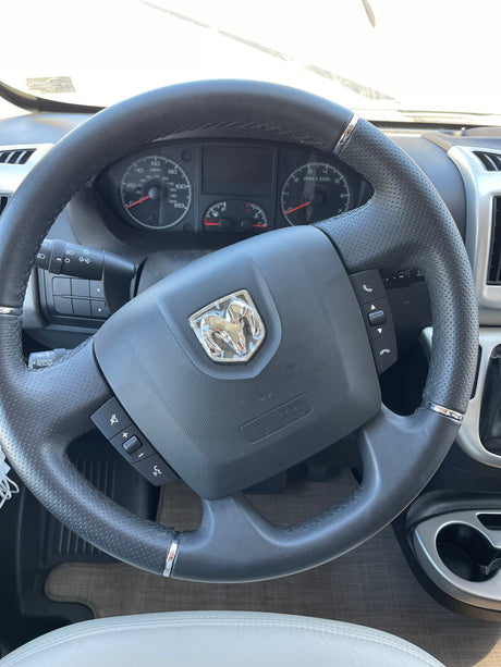 Interior of an RV rental showing the steering wheel with Ram logo, dashboard, and controls.