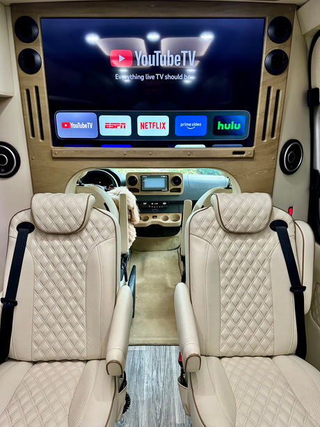 Luxurious rv rental interior featuring quilted cream seats and a TV displaying YouTube TV, ESPN, Netflix, Prime Video, and Hulu.