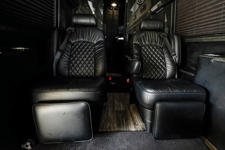 Two premium black leather captain's chairs create a luxurious experience in this RV rental interior.