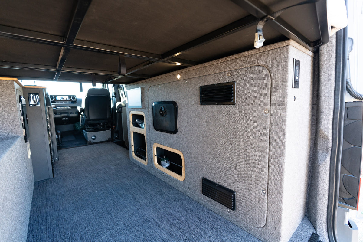 Spacious camper van interior, perfect for an RV rental adventure. Features custom storage, bed platform, and control panel. — photo 15