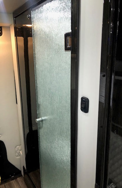 Modern compact shower in an RV rental, featuring a textured glass door with a silver handle and an adjacent light switch. — photo 10