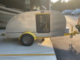  parked on asphalt.|This silver teardrop camper
