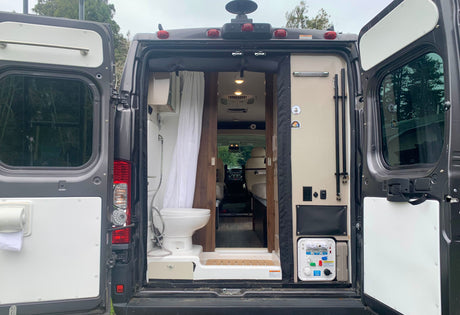 Inside an **rv rental**, the rear features a space-saving bathroom with a toilet, shower, and a visible utility panel.